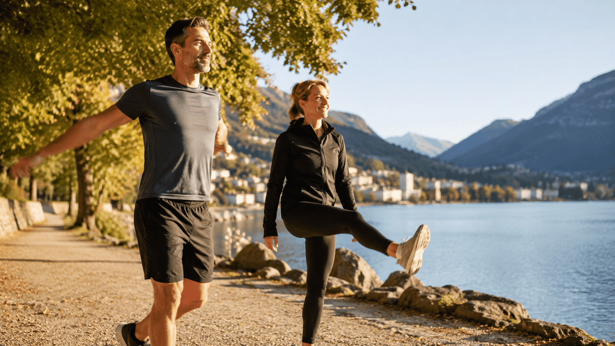 Ein Mann und eine Frau machen in der Morgensonne Dehnübungen am Ufer eines Sees